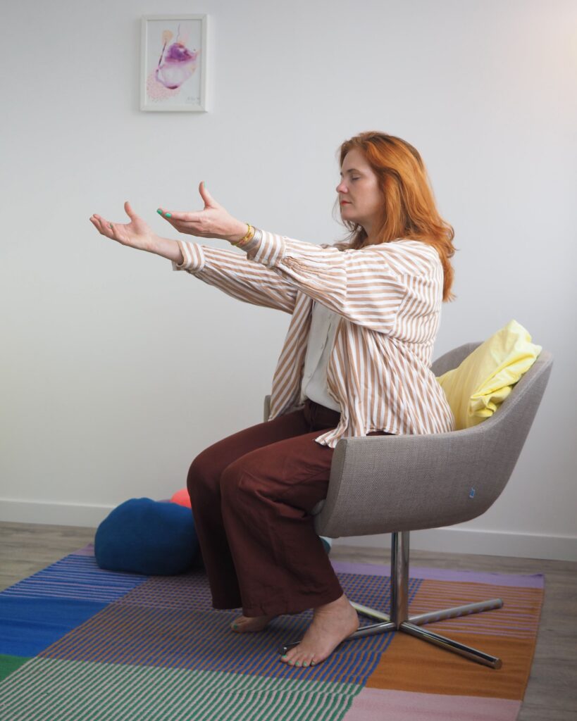 Sophrologue Biarritz : Femme assise levant les bras pendant un exercice de sophrologie pour libérer la charge mentale